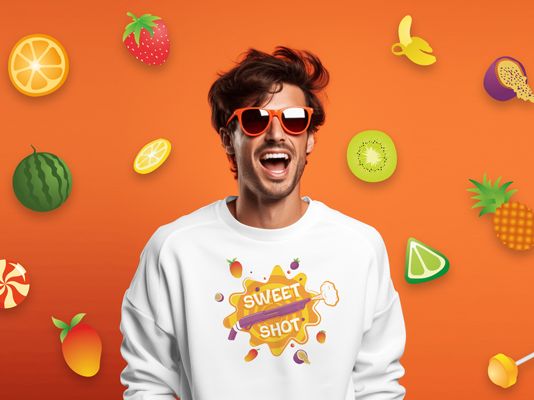 Мужчина в белом свитшоте с принтом «Sweet Shot» на фоне фруктов и конфет